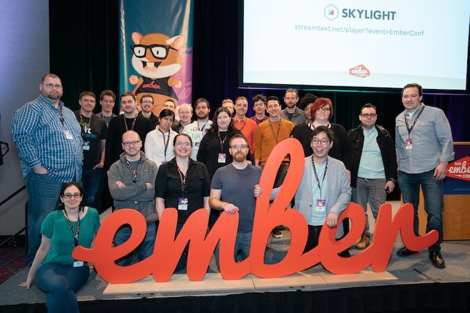 Ember core team members gather around the Ember sign at EmberConf